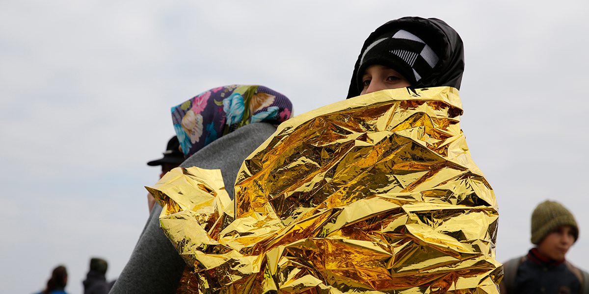 Woman covered with emergency blanket after her arrival in Greece.